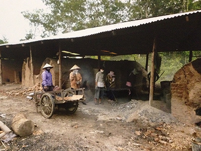 炭焼き窯で働くラオスの村人。女性の姿も見えます。